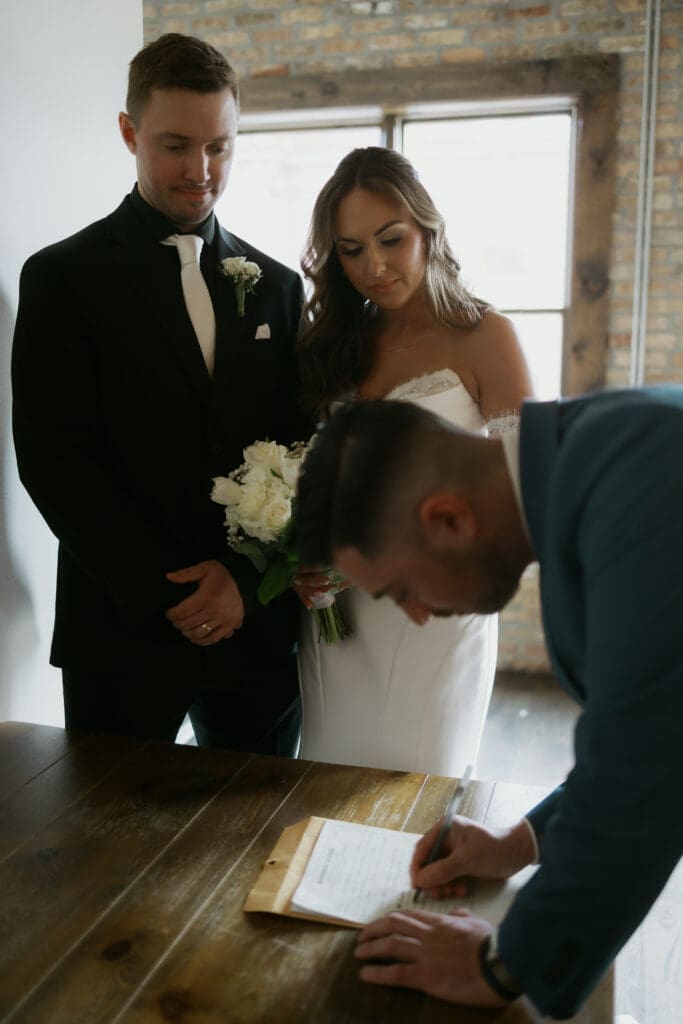 Couple shares a quiet moment while signing their marriage license at Ethereal Events in Woodstock, Illinois, after their wedding ceremony.