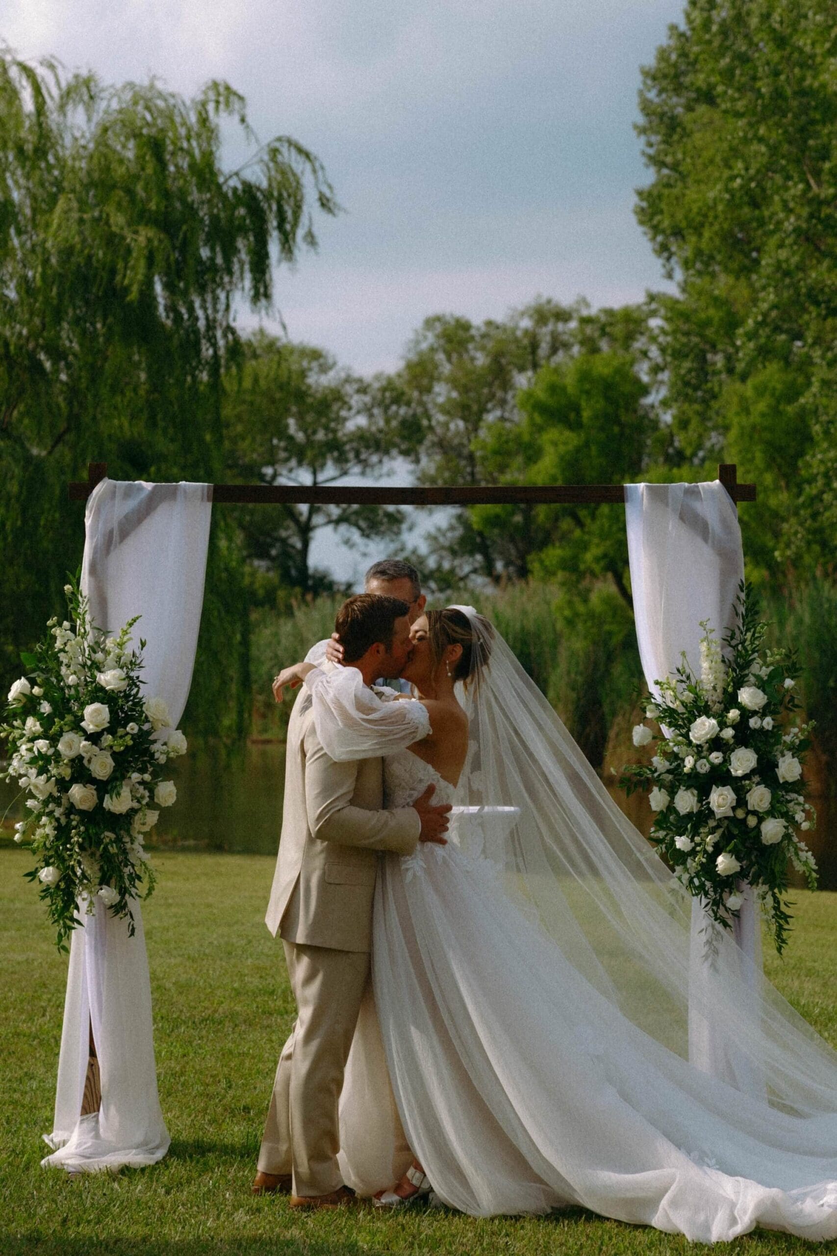 Couple sharing their first kiss during their wedding ceremony on the family farm in Chicago Illinois by Nicole Kilday